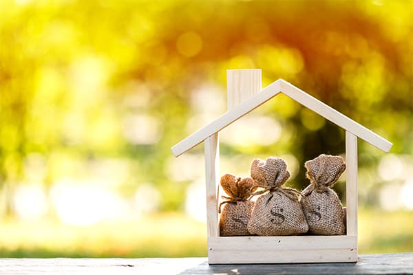 Business-loans-for-real-estate-concept,-a-money-bags-put-in-a-model-home-on-the-table-on-bokeh-background-in-the-public-park.